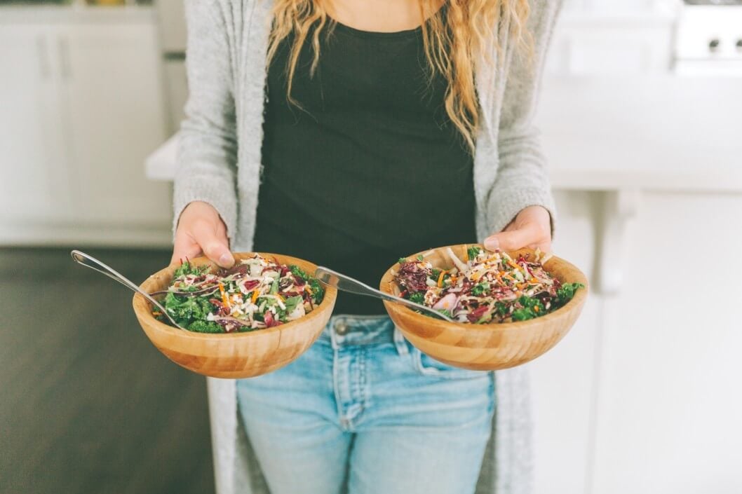 Frau bringt zwei vegane Bowls in die Küche