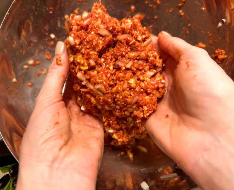 Masse aus Zwiebeln, Tomatenmark und Reiswaffeln wird über einer Edelstahlschüssel in der Hand gehalten