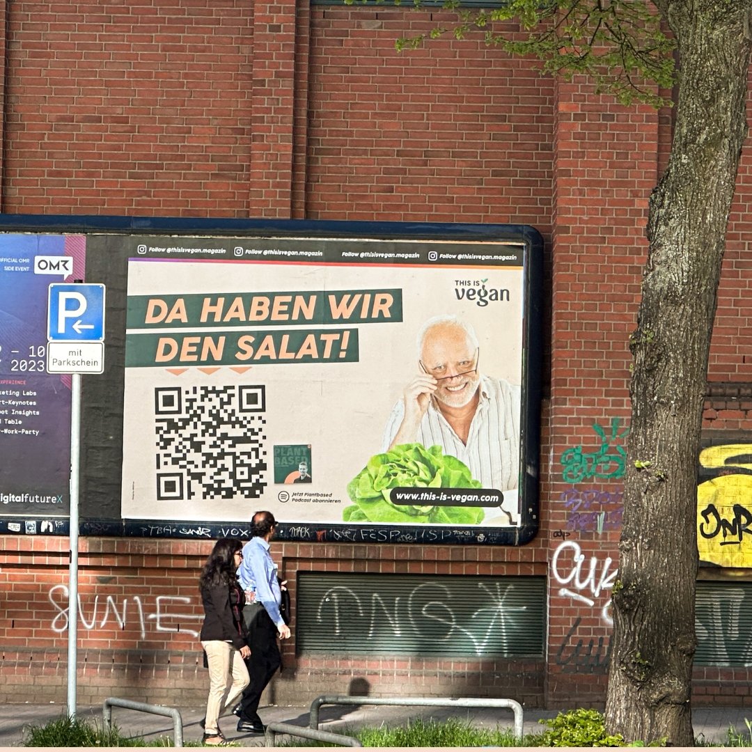 Werbeplakat an einem Backsteinhaus mit Werbung von this is Vegan. Auf dem Plakat ist ein Mann zu sehen und ein grüner Salat und die Aufschrift "da haben wir den Salat"