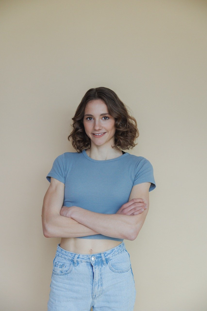 Vegan Influencerin Maya Leinenbach aka Fitgreenmind mit verschränkten Armen vor einer einfarbigen Wand
