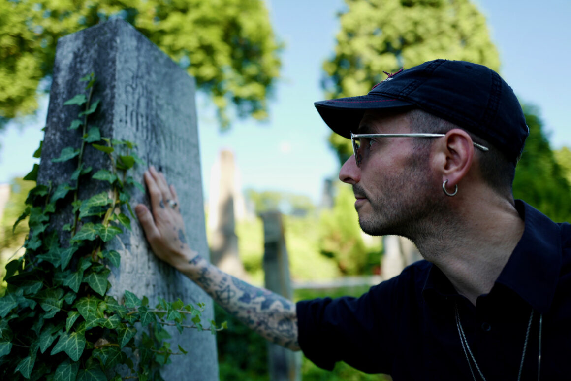 Kriminalbiolgoe Dr. Mark Benecke neben einen Skelett vor einem Grabstein in Transilvanien
